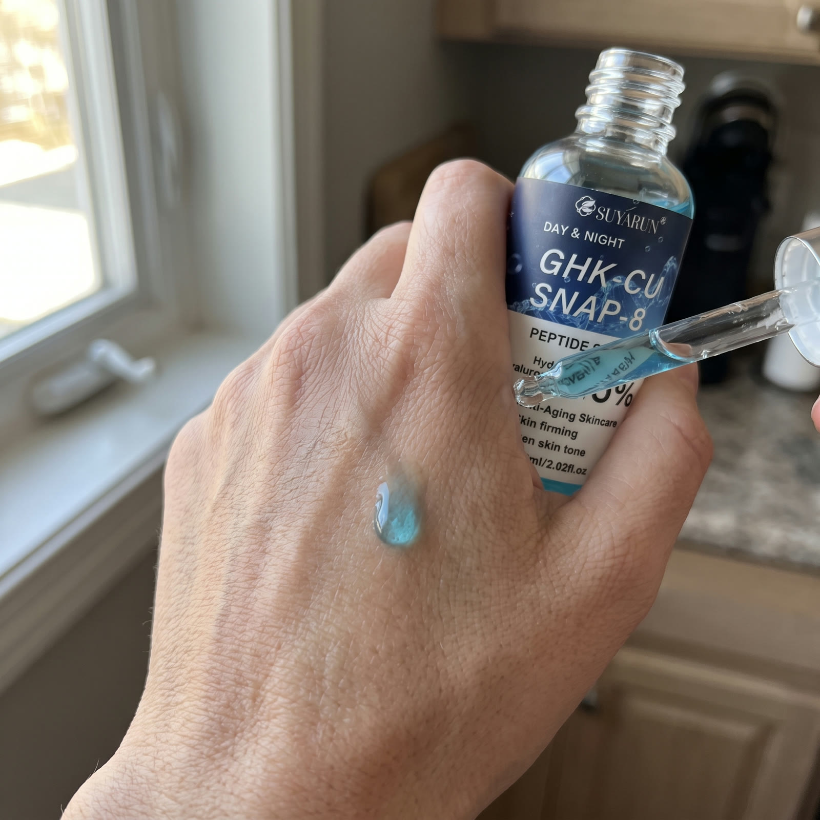 Blue serum drop on the back of a hand
